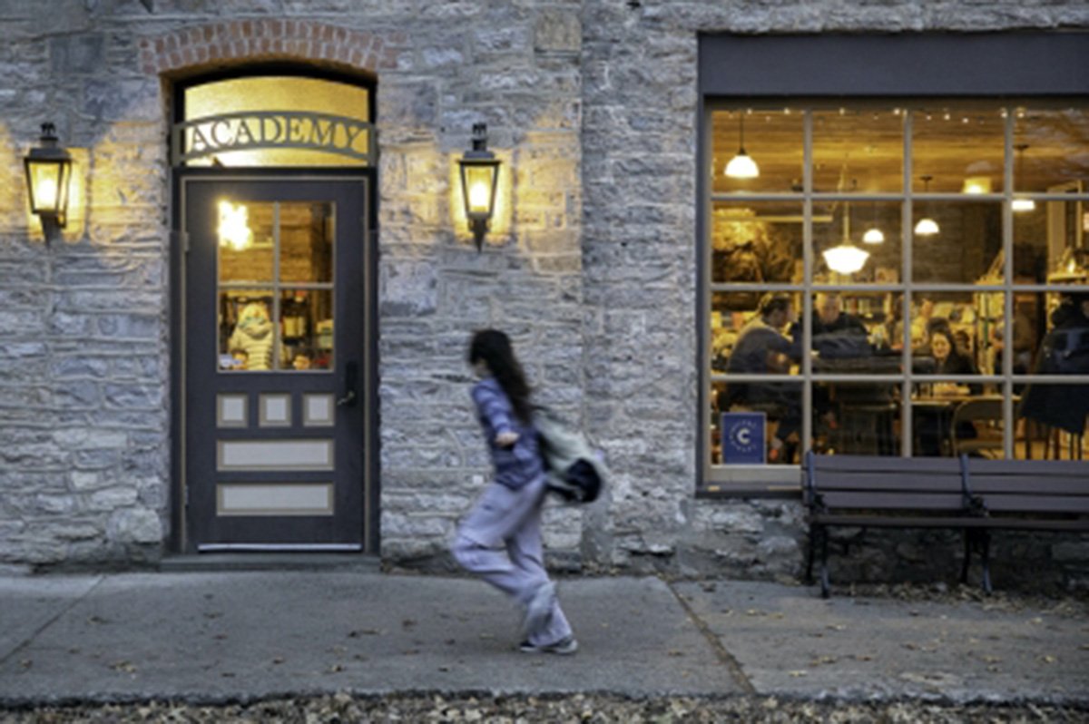A Stockade District streetscape in Kingston — Dutch stone façade, lit lanterns flanking the 'Academy' door