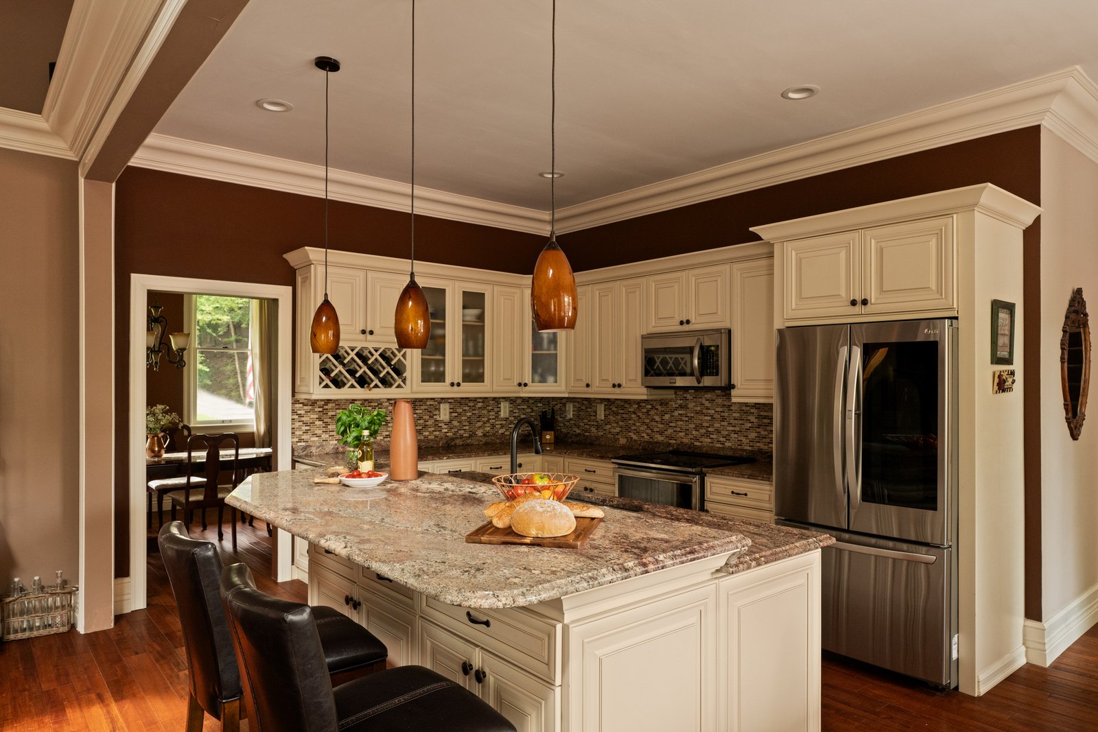 A kitchen with cream cabinetry, granite counters and a central island.