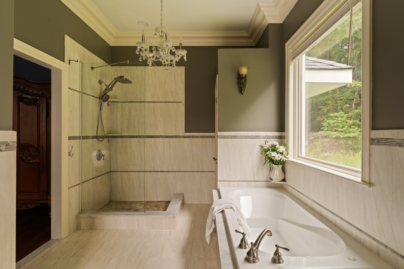 A tiled bathroom with a soaking tub set beneath a window.