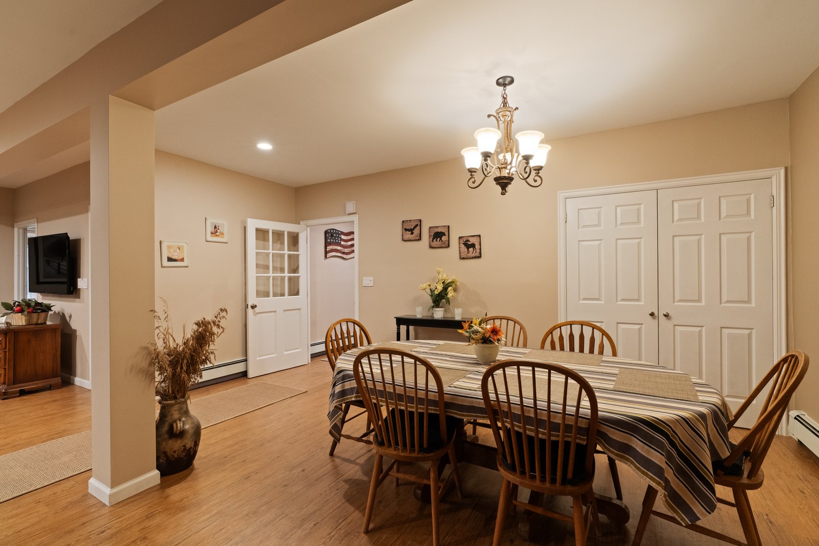 A dining table and chairs beneath a chandelier in a lower-level room.
