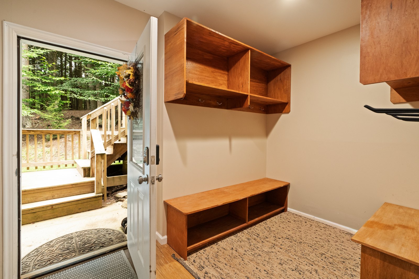 A walk-out entry with steps rising to an open door and trees beyond.