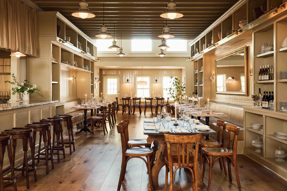 Little Goat — the dining room with lowered beams, cream shelving, and candlelight