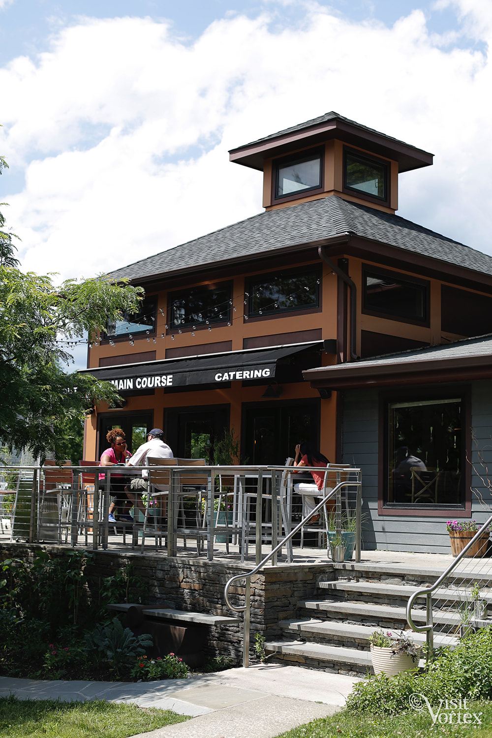 The Main Course storefront at 175 Main Street, New Paltz — pyramidal roof, awning, patio with diners