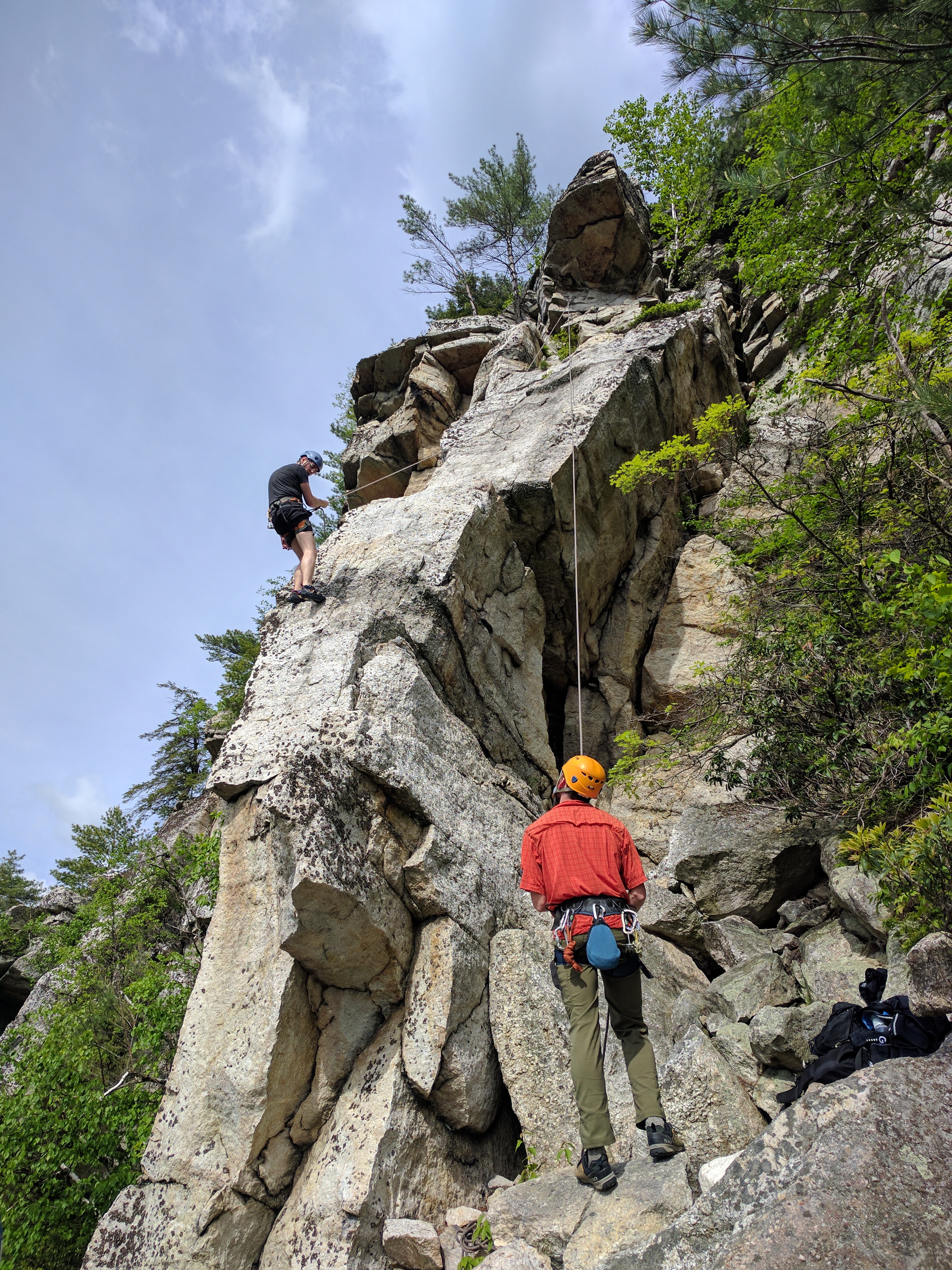 A climber on the Shawangunk cliffs at Mohonk Preserve — vertical white quartz face, rope, chalk bag, technical route