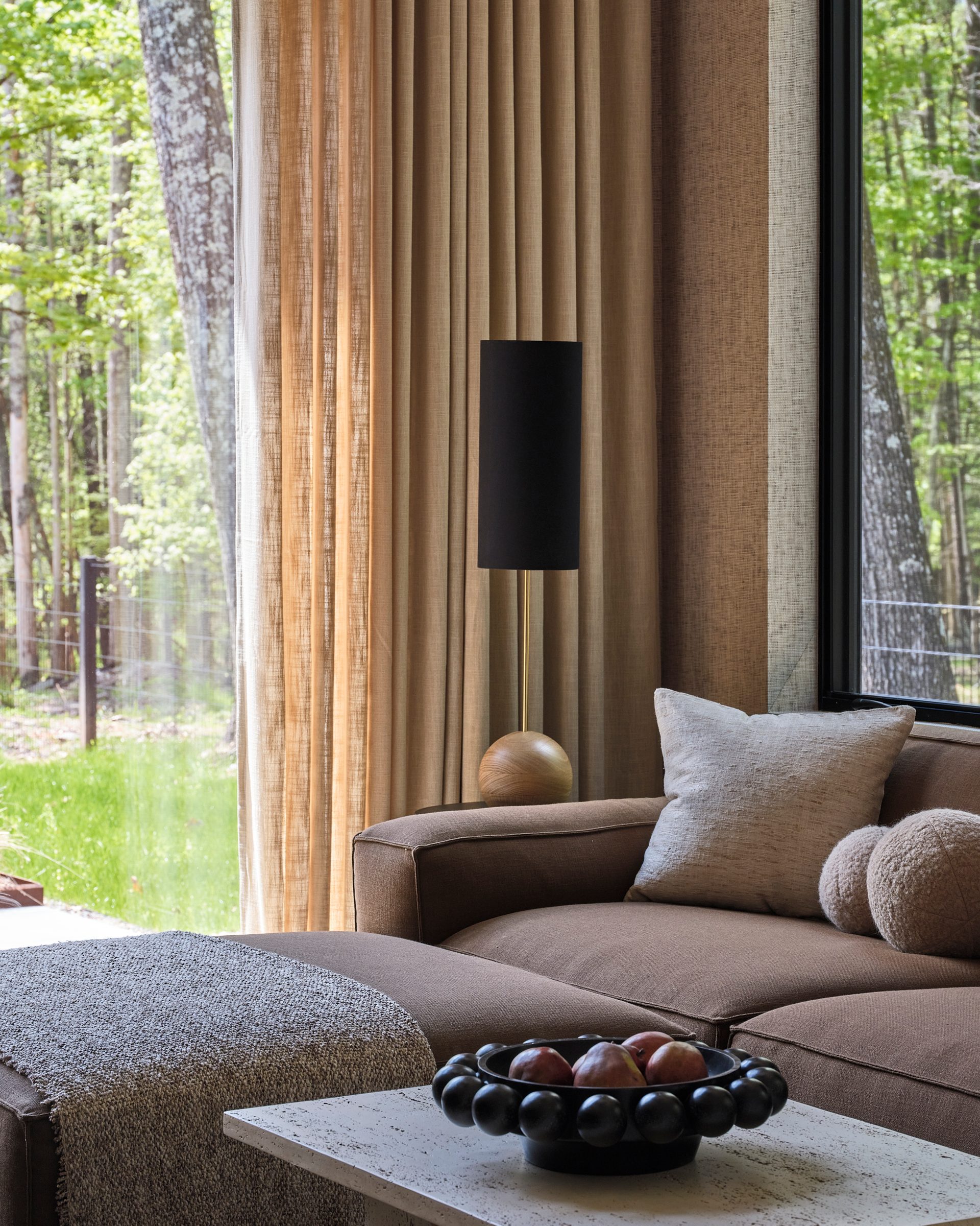 A curved sofa beside a floor-to-ceiling window onto the trees.