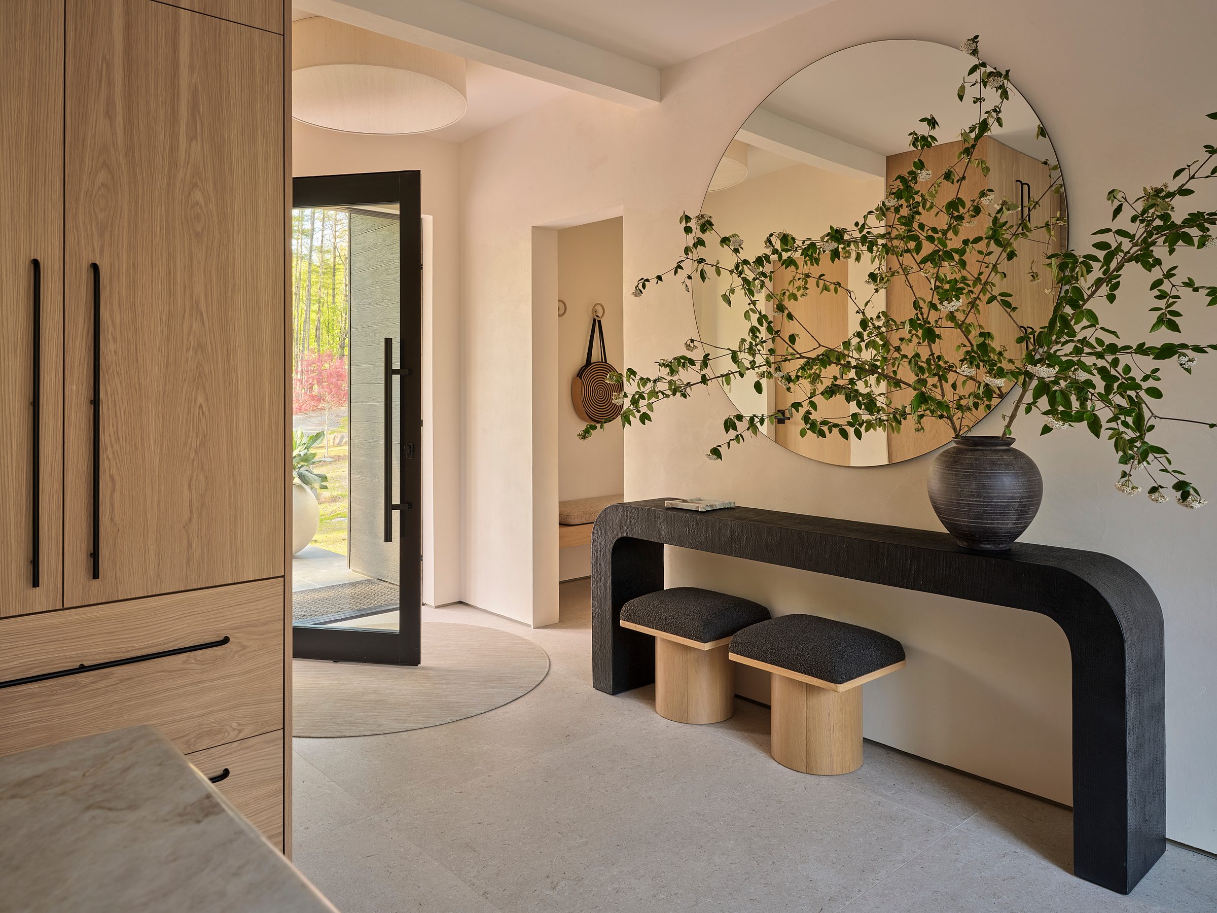 An entry with a glass pivot door, a console and a bench.