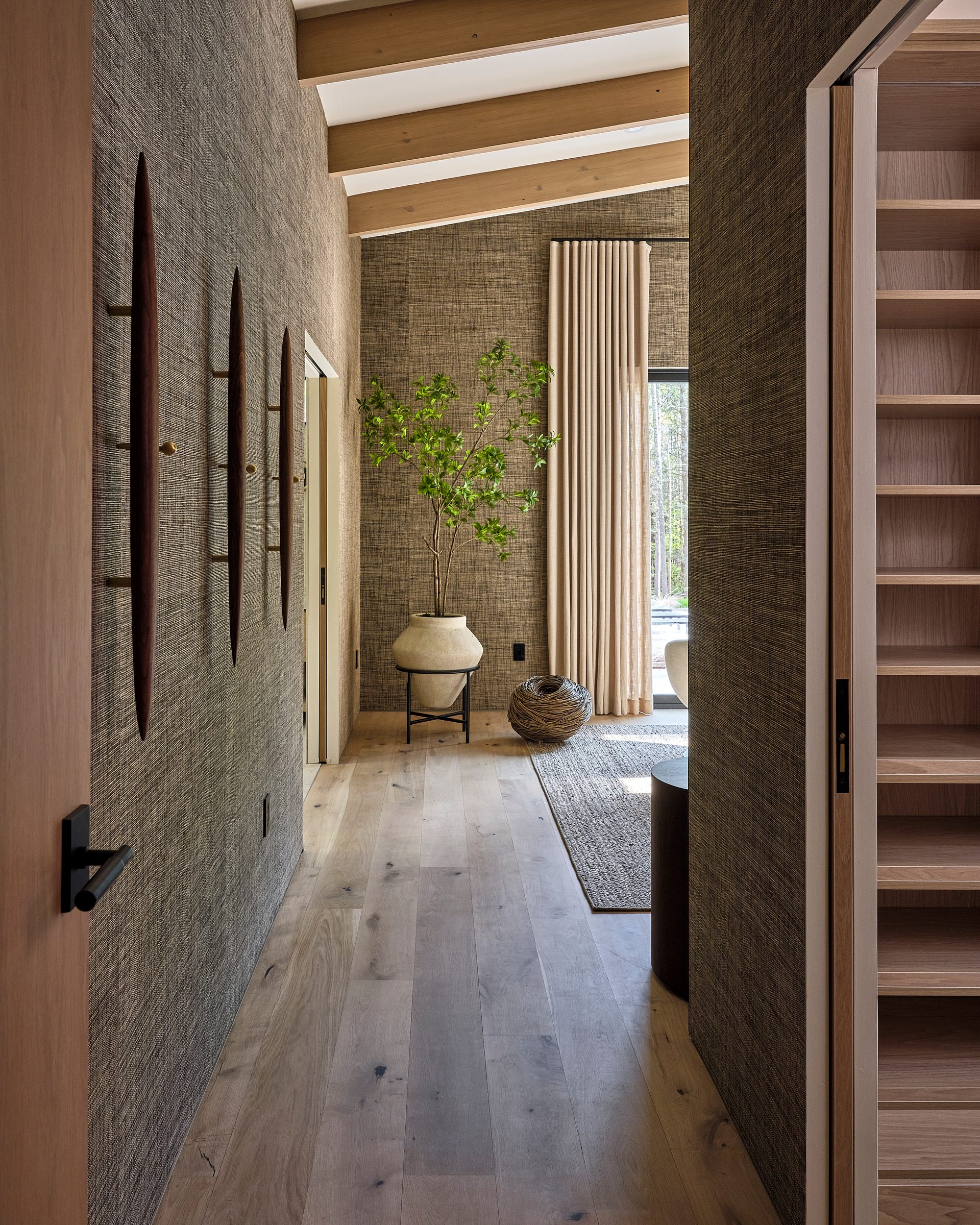 A hallway with a textured wall and built-in shelving, leading to a bedroom.