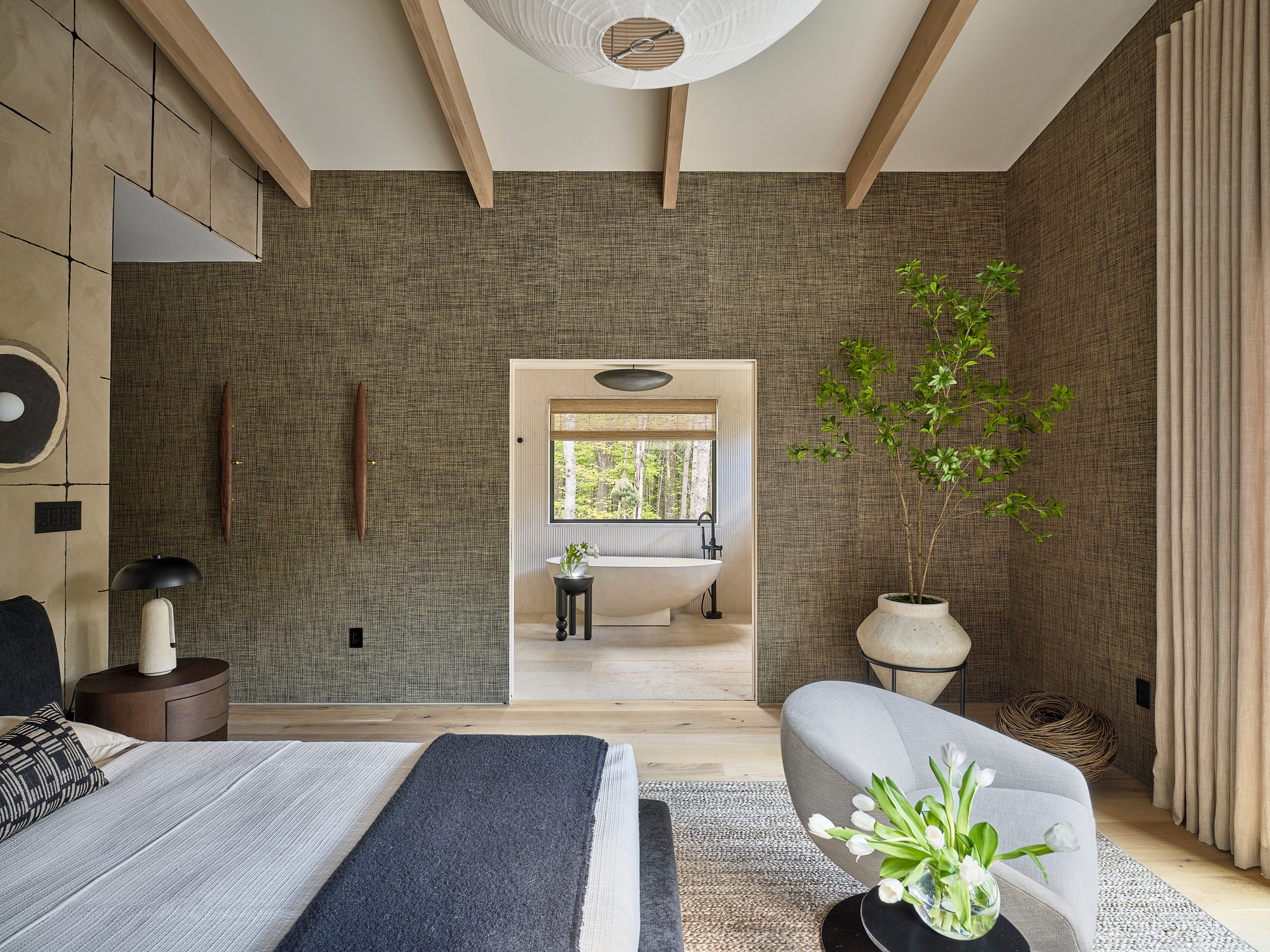 A bedroom with grasscloth walls opening onto a bath.