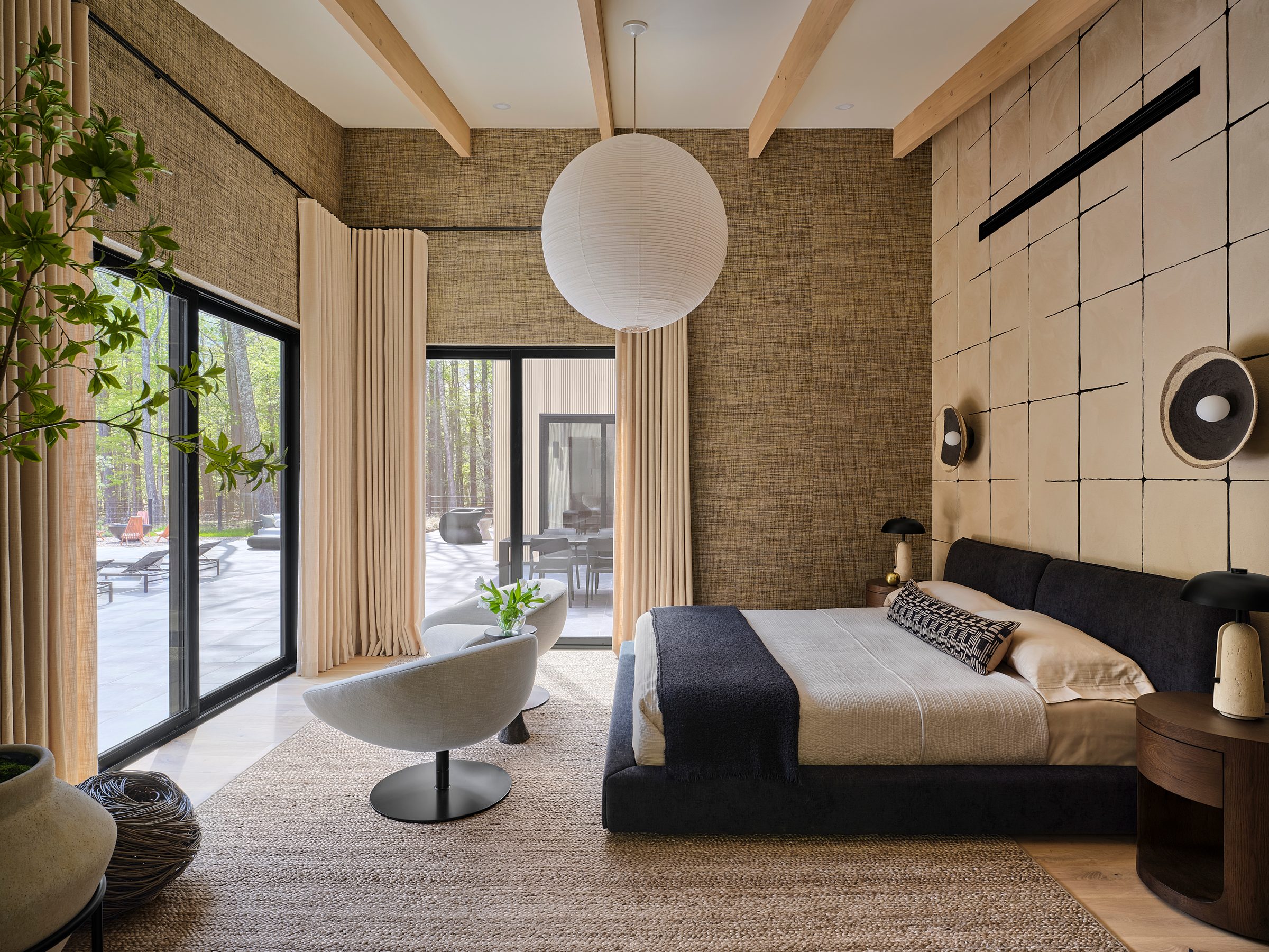 A bedroom with a paper pendant, grasscloth walls and sliders to the terrace.