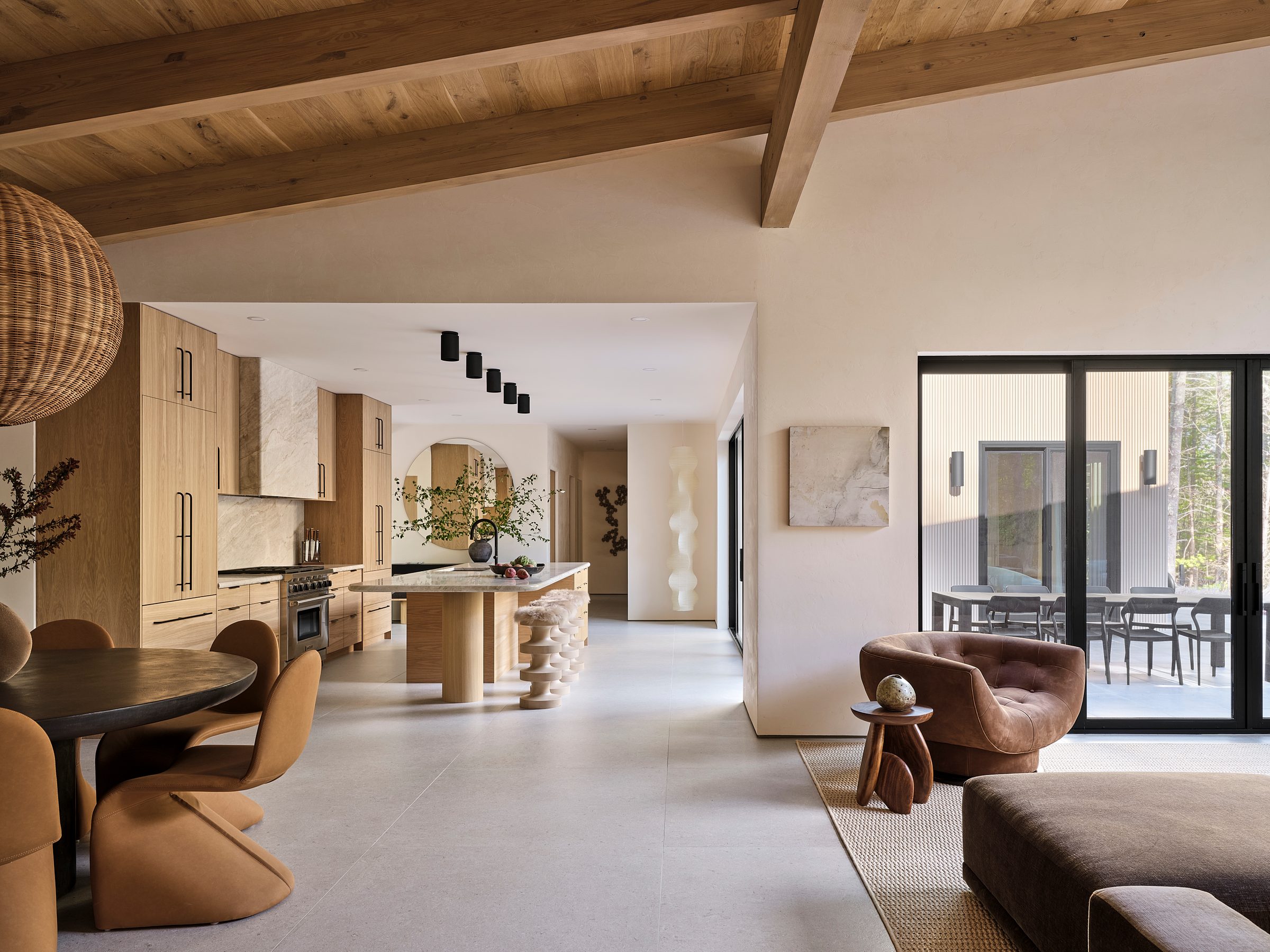 An open kitchen, dining and living space under exposed beams.