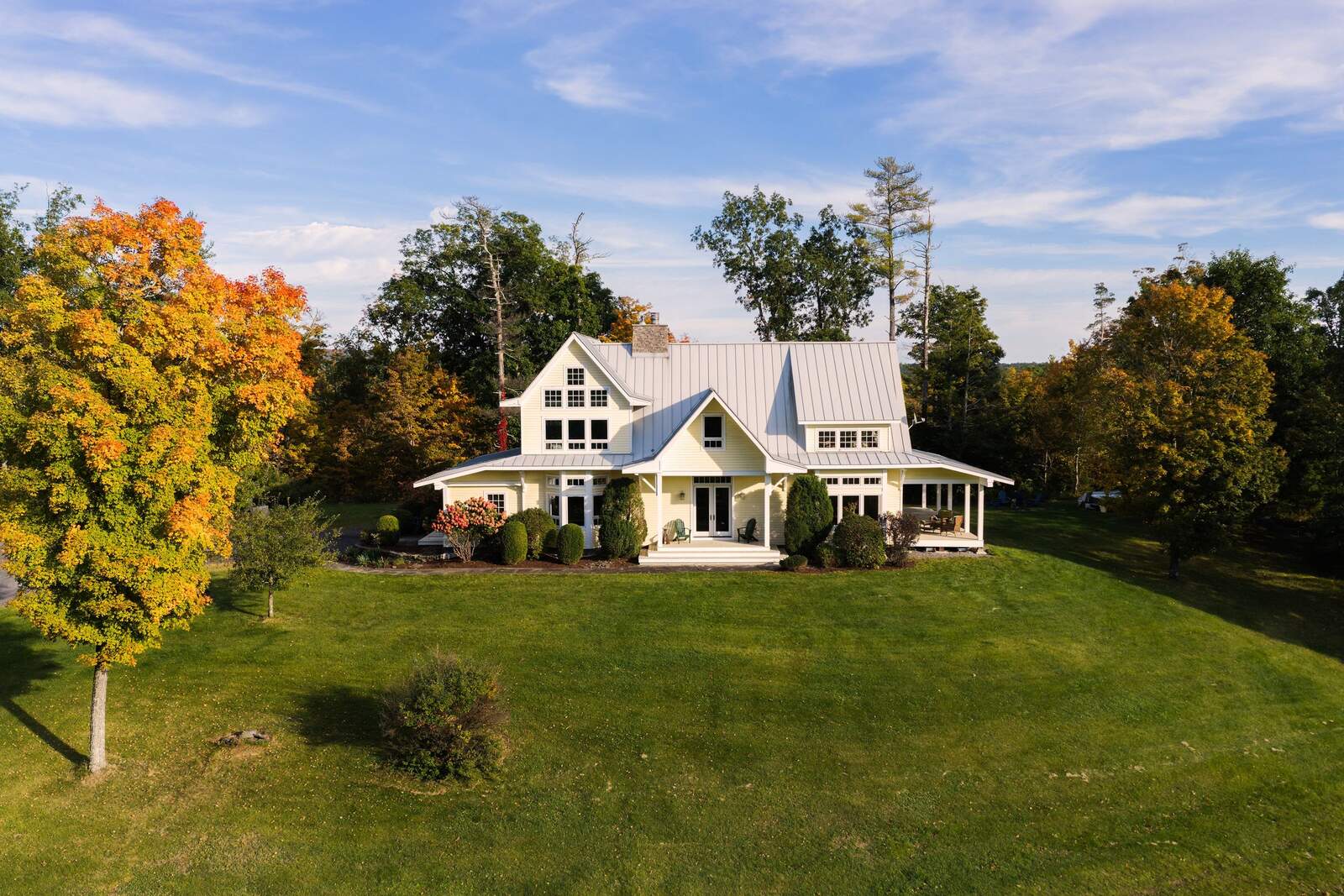 The front of the house across the lawn, framed by autumn trees.