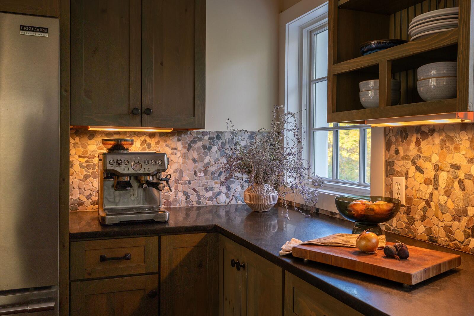 A kitchen corner with a stone-tile backsplash and an espresso machine.