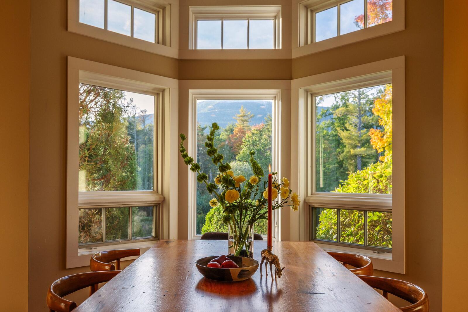 The dining table set before the bay windows.