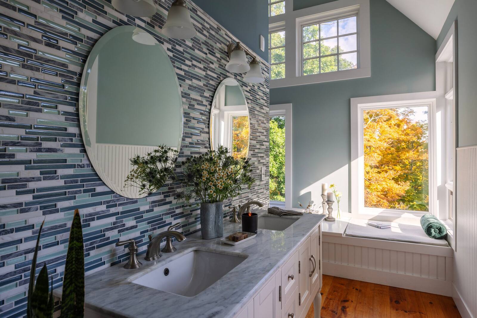 The primary bath, a round mirror on a tiled wall.