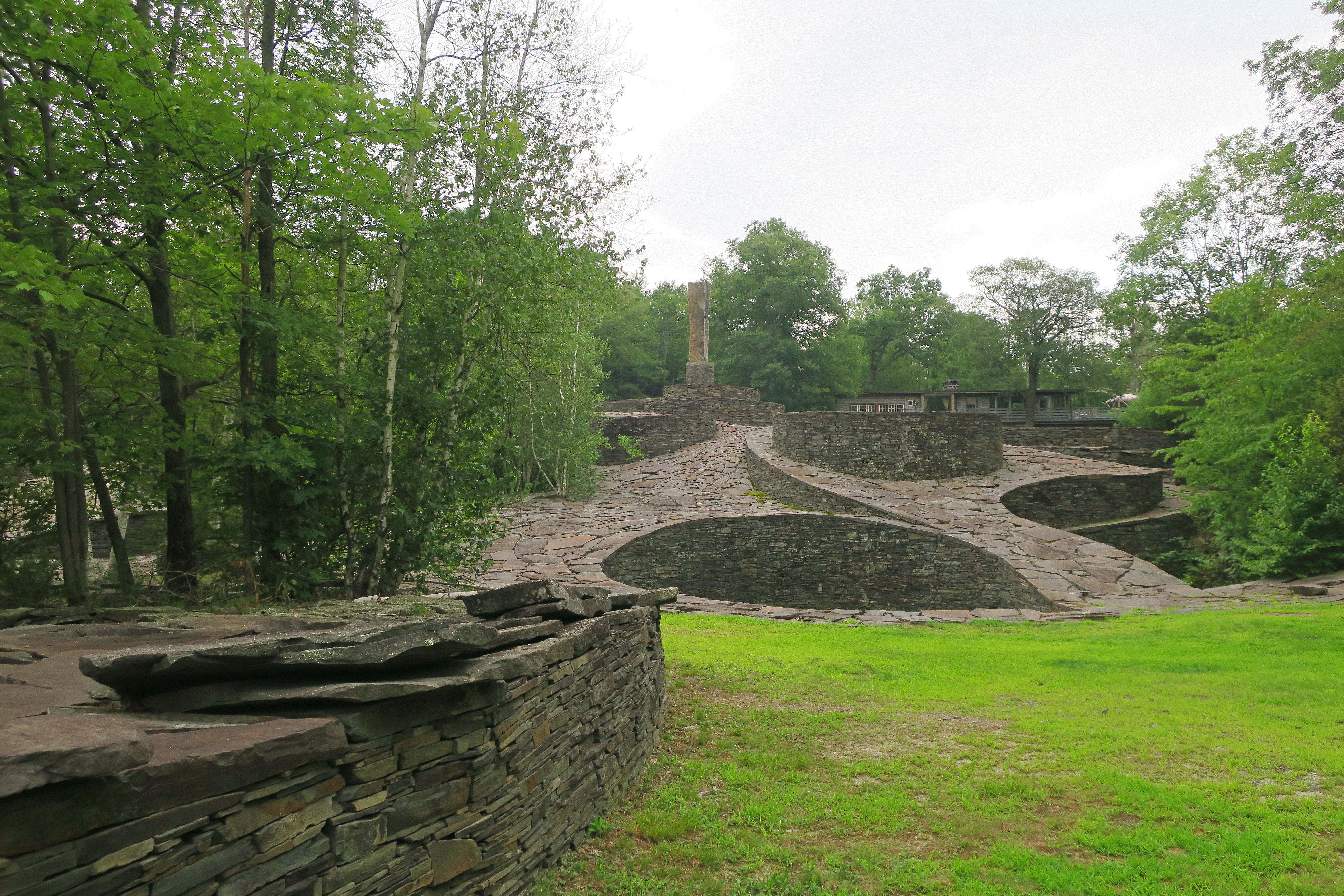 A wide view across Opus 40 — the dry-laid bluestone ramps and terraces with the Catskill Mountains beyond
