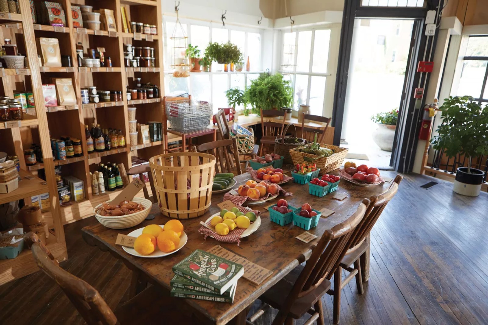 The interior at Rosie General — wood-plank floors, retail shelves, a farm table of fresh produce by the open front door