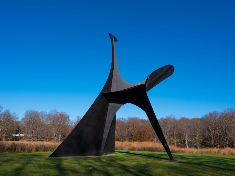 Alexander Calder's The Arch (1975) — monumental black steel sculpture against an autumn meadow and clear blue sky